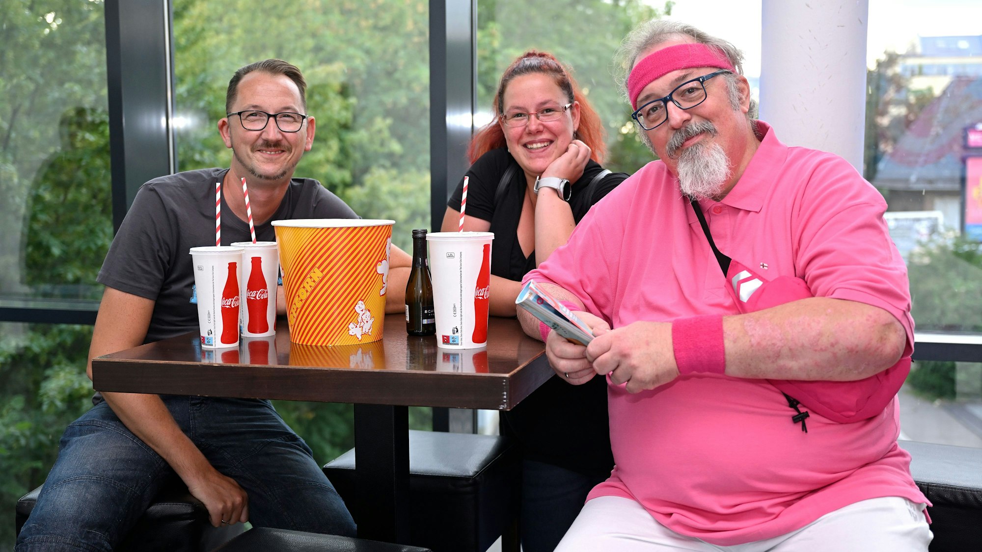 Die Bekannten sitzen an einem Tisch im Vorraum des Kinos.