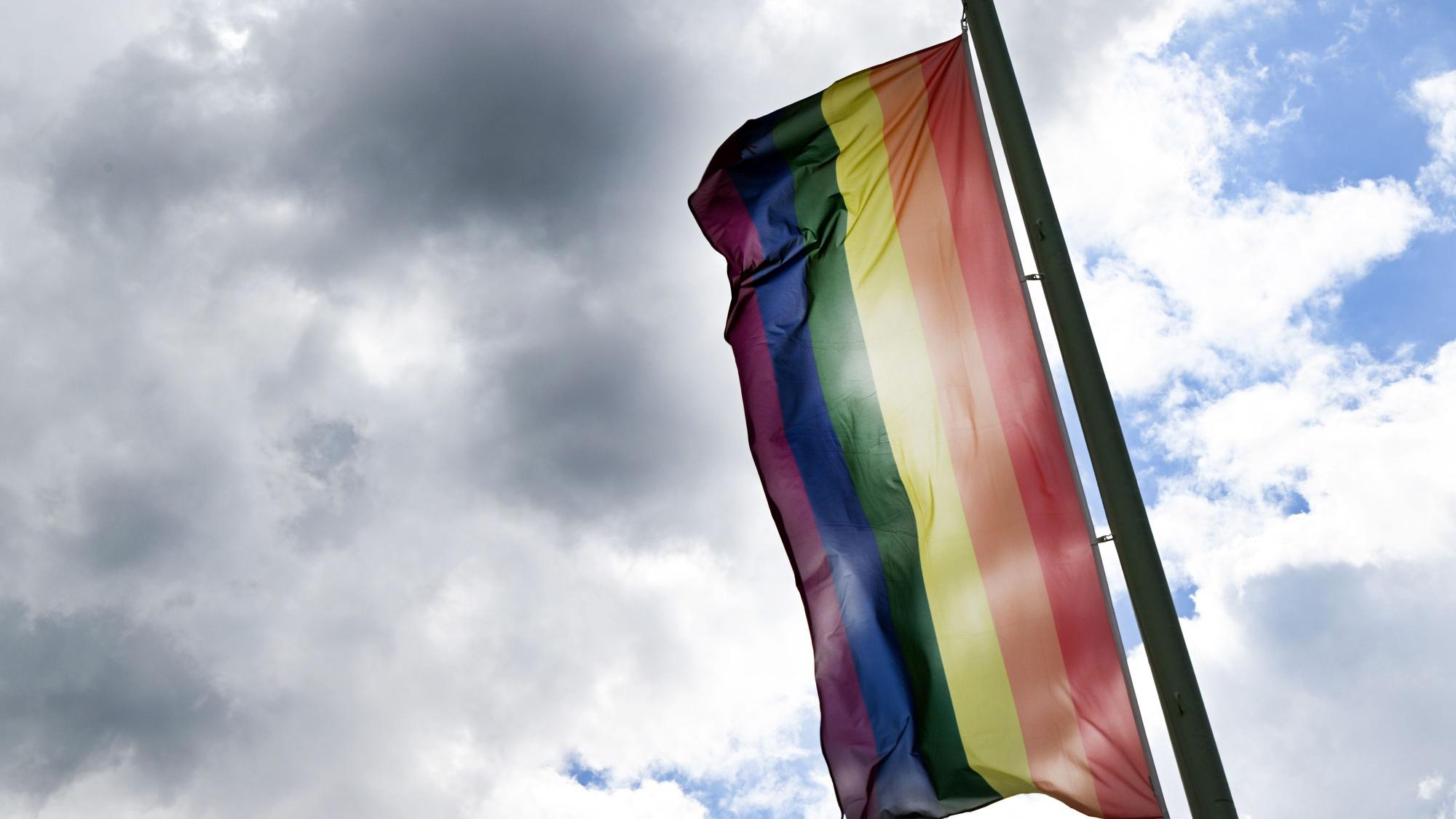 Eine bunte Regenbogenflagge weht im Wind.