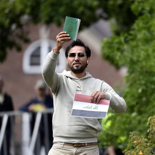 Ein Demonstrant hält eine Kopie des Korans gemeinsam mit einer irakischen Fahne vor der irakischen Botschaft in die Luft.