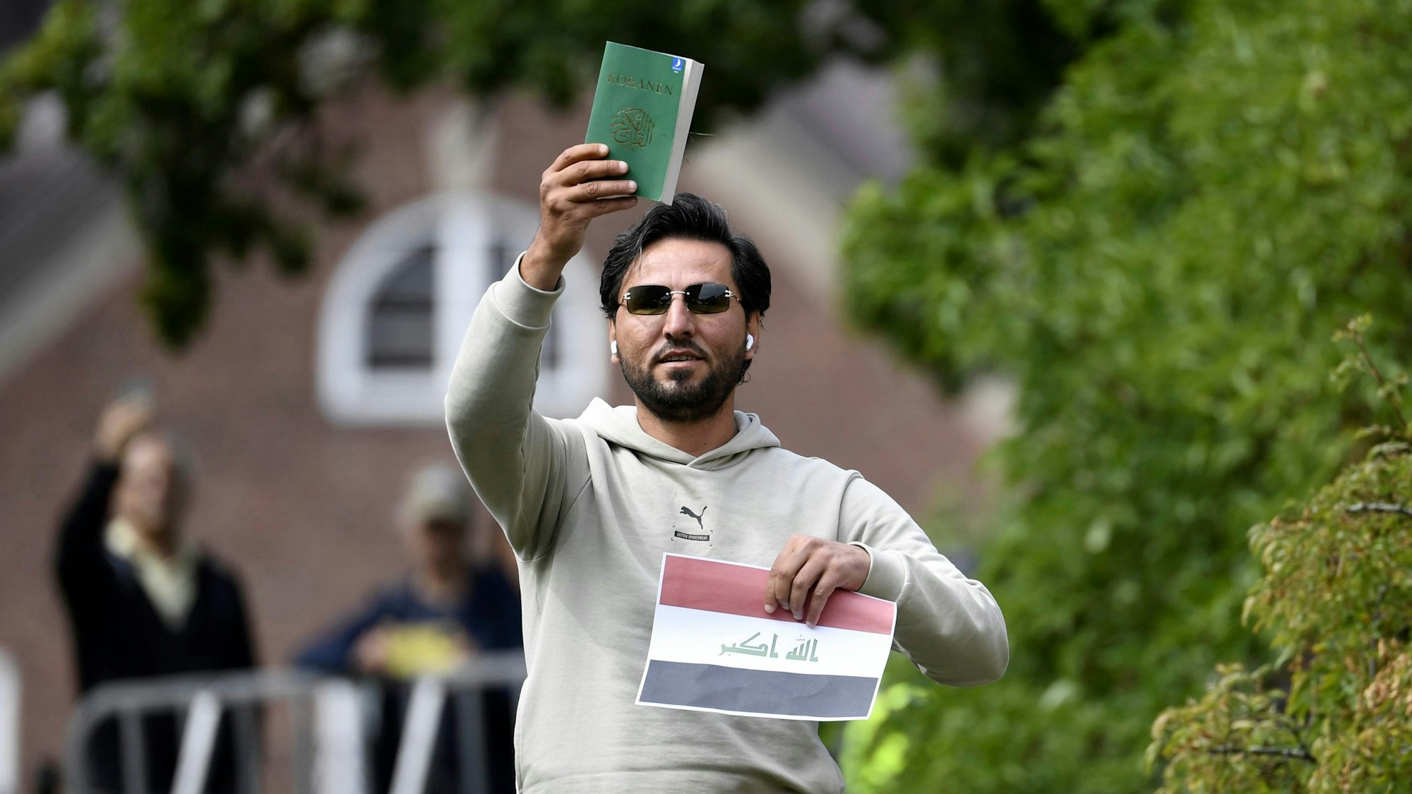Ein Demonstrant hält eine Kopie des Korans gemeinsam mit einer irakischen Fahne vor der irakischen Botschaft in die Luft.