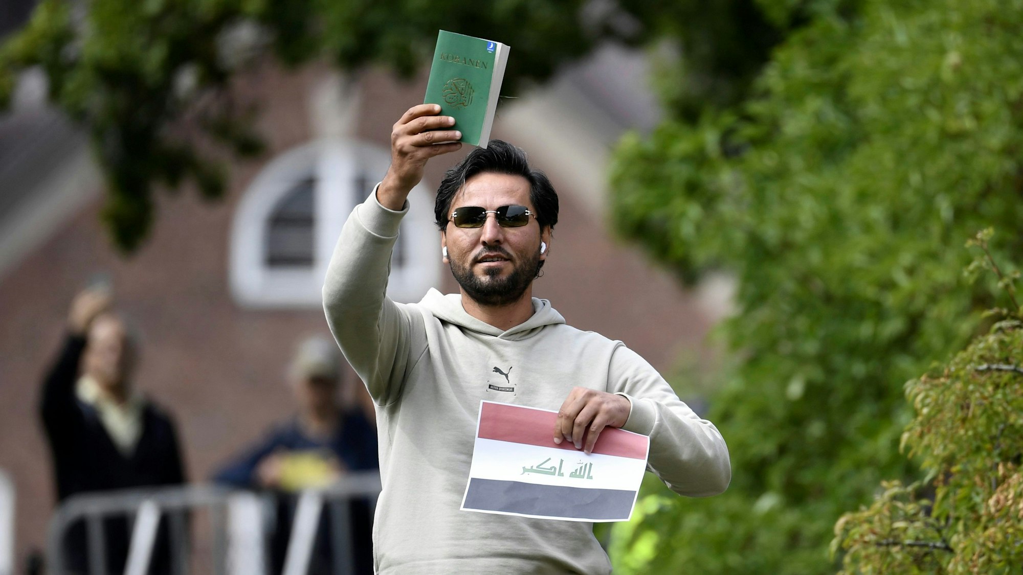 Ein Demonstrant hält eine Kopie des Korans gemeinsam mit einer irakischen Fahne vor der irakischen Botschaft in die Luft.
