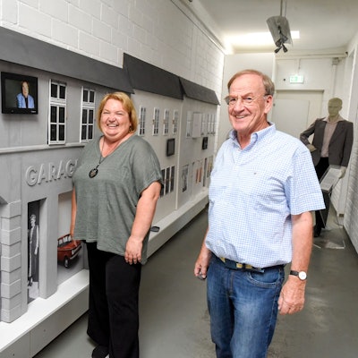 Eine Frau und ein Mann stehen vor einer Kulisse, die historische Gebäude zeigt.