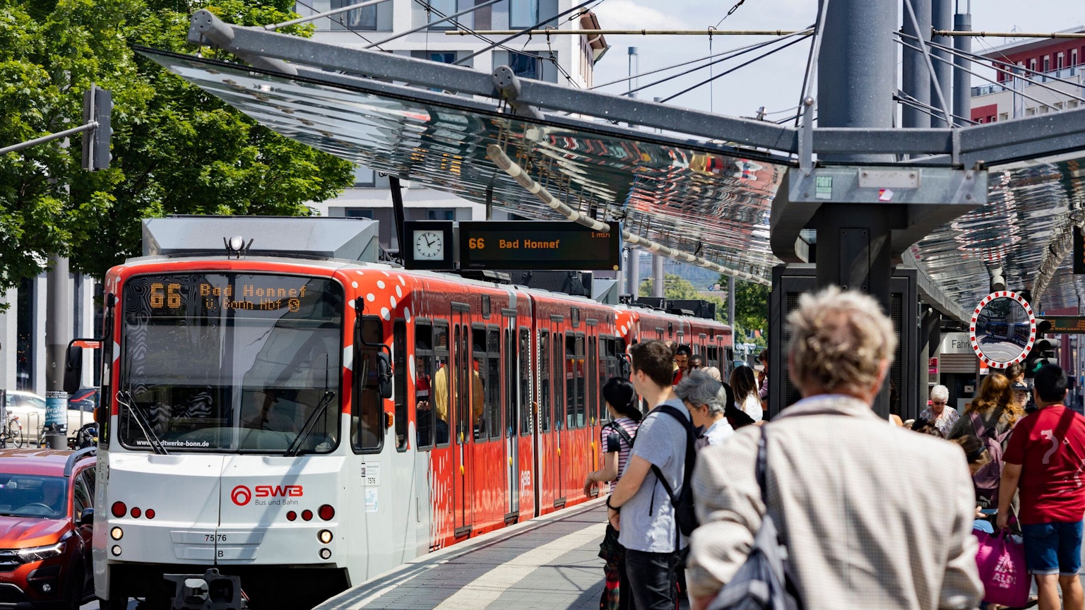 Menschen stehen in Bonn am Gleis. Gerade fährt die Linie 66 Richtung Bad Honnef ein.