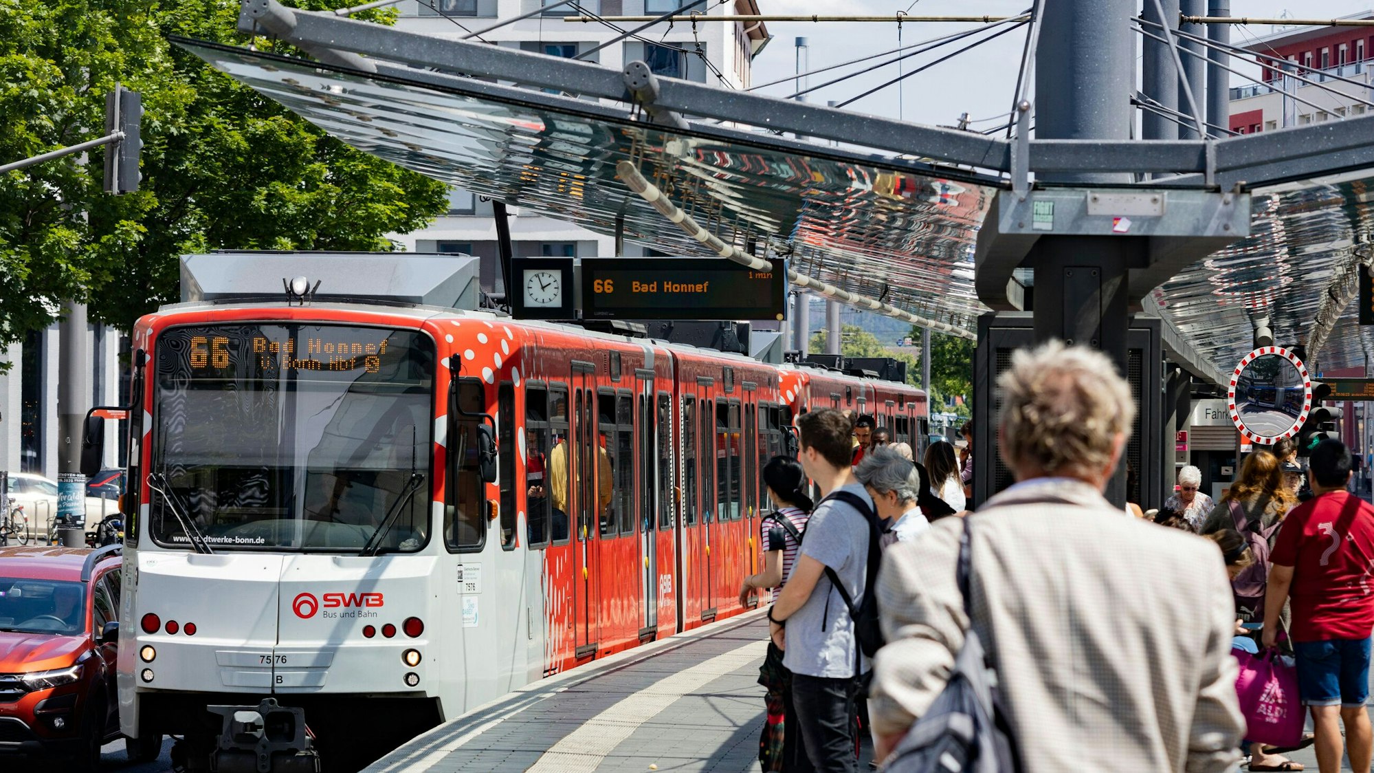 Menschen stehen in Bonn am Gleis. Gerade fährt die Linie 66 Richtung Bad Honnef ein.