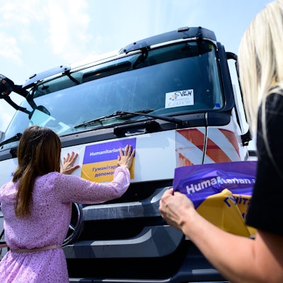 Eine Frau klebt einen Aufkleber auf ein Spezialfahrzeug, das in die Ukraine gefahren wird.