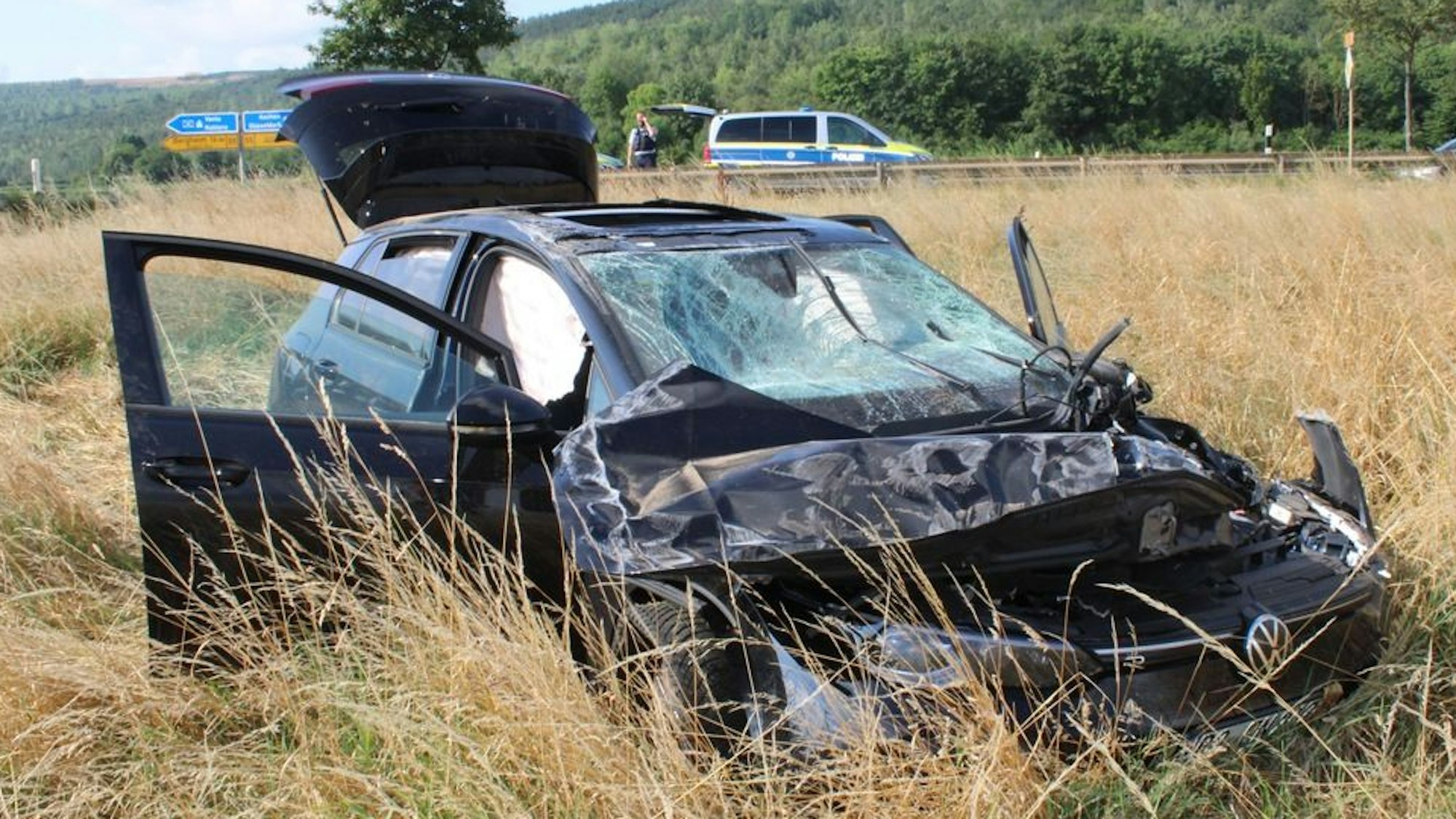 Das Bild zeigt ein völlig zerstörtes Auto in einem Feld