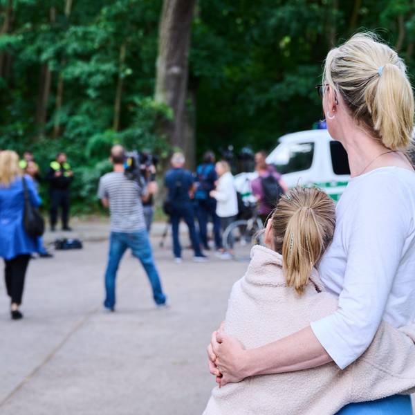 Eine Anwohnerin und ihre Tochter sehen dem Treiben von Journalisten und Polizei zu, während Tierexperten und Polizeibeamten in einem Waldgebiet in Zehlendorf stehen. Eine frei laufende Raubkatze sollte in der Gemeinde Kleinmachnow in Brandenburg gesichtet worden sein. Am Freitag ist die Suche eingestellt worden.