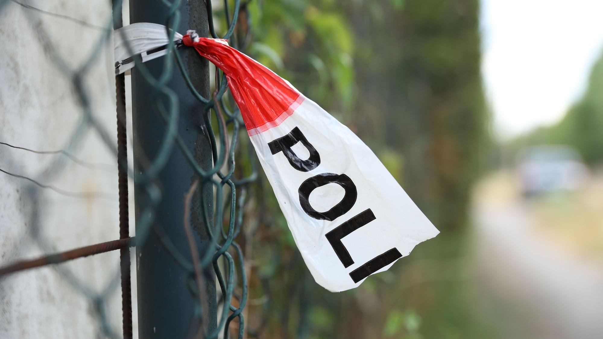 Polizeiabsperrband weht an einem Zaun. (Symbolbild)
