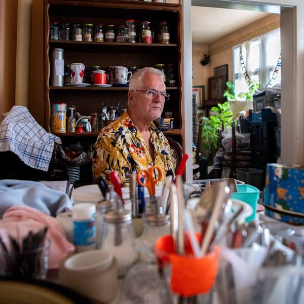 Ein Mann sitzt an einem Tisch. Darauf sind unscharf zahlreiche Dinge zu sehen, die er nach der Flut aus seinem Café gerettet hat.