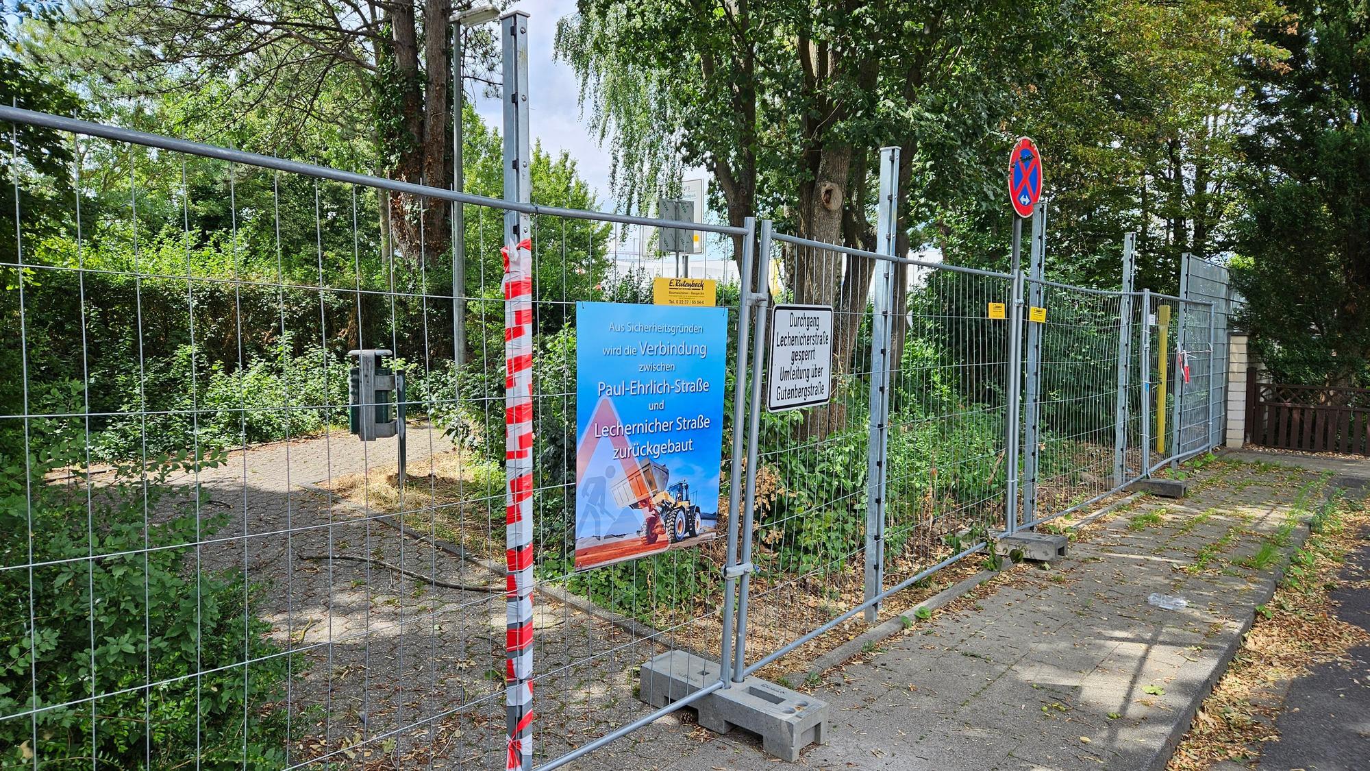 Ein Bauzaun versperrt einen Fußweg am Ende einer Straße.