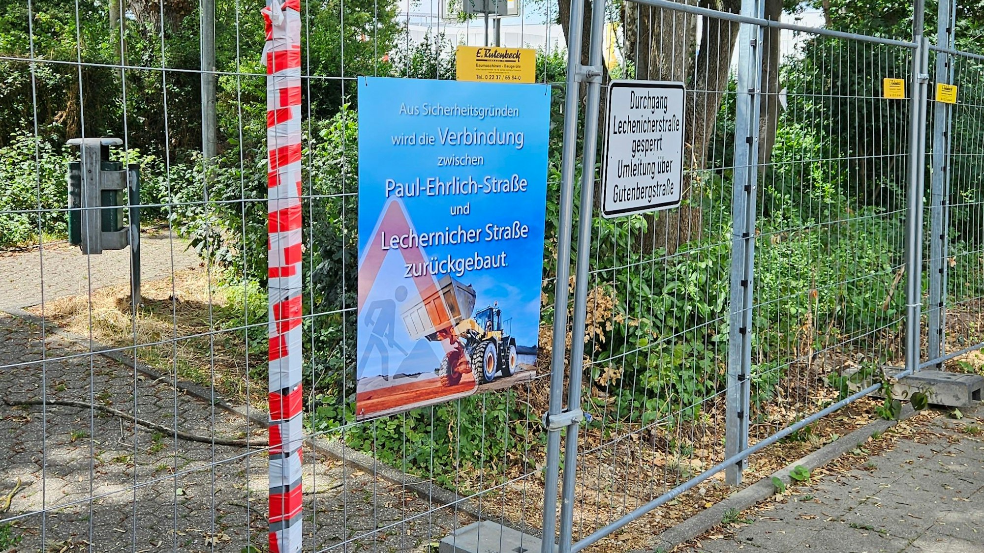 Das Bild zeigt einen Bauzaun vor einem Fußweg.