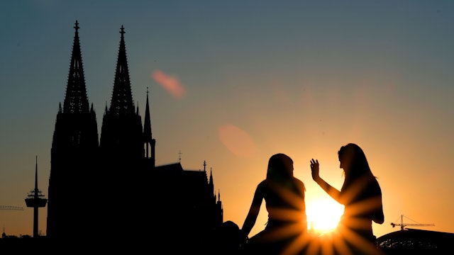 Zwei Frauen sitzen im Sonnenuntergang am Rheinboulevard vor dem Dom. (zu dpa «Drei Viertel der Deutschen finden Kirchensteuer nicht zeitgemäß»)