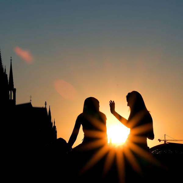 Zwei Frauen sitzen im Sonnenuntergang am Rheinboulevard vor dem Dom. (zu dpa «Drei Viertel der Deutschen finden Kirchensteuer nicht zeitgemäß»)