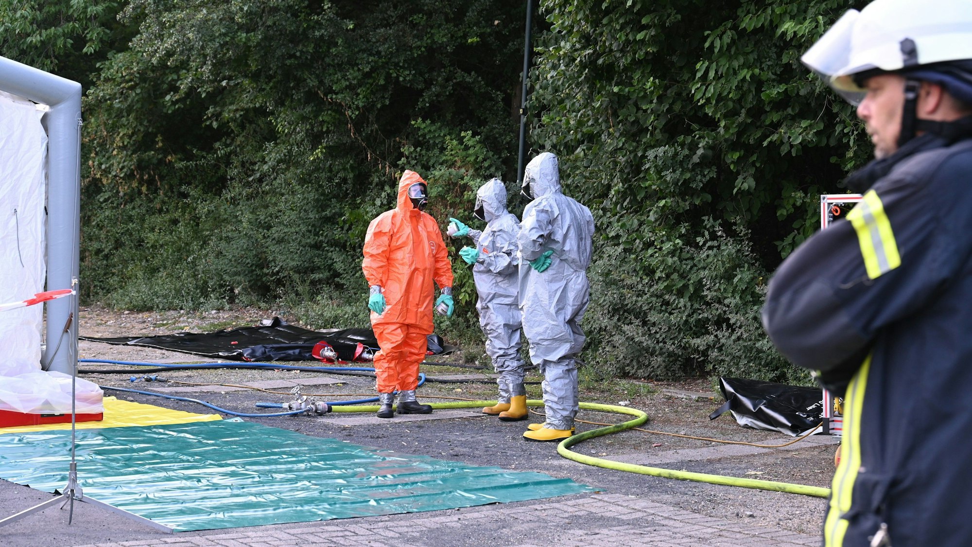 Das Foto zeigt Feuerwehrleute in Schutzanzügen vor der Erftlagune.