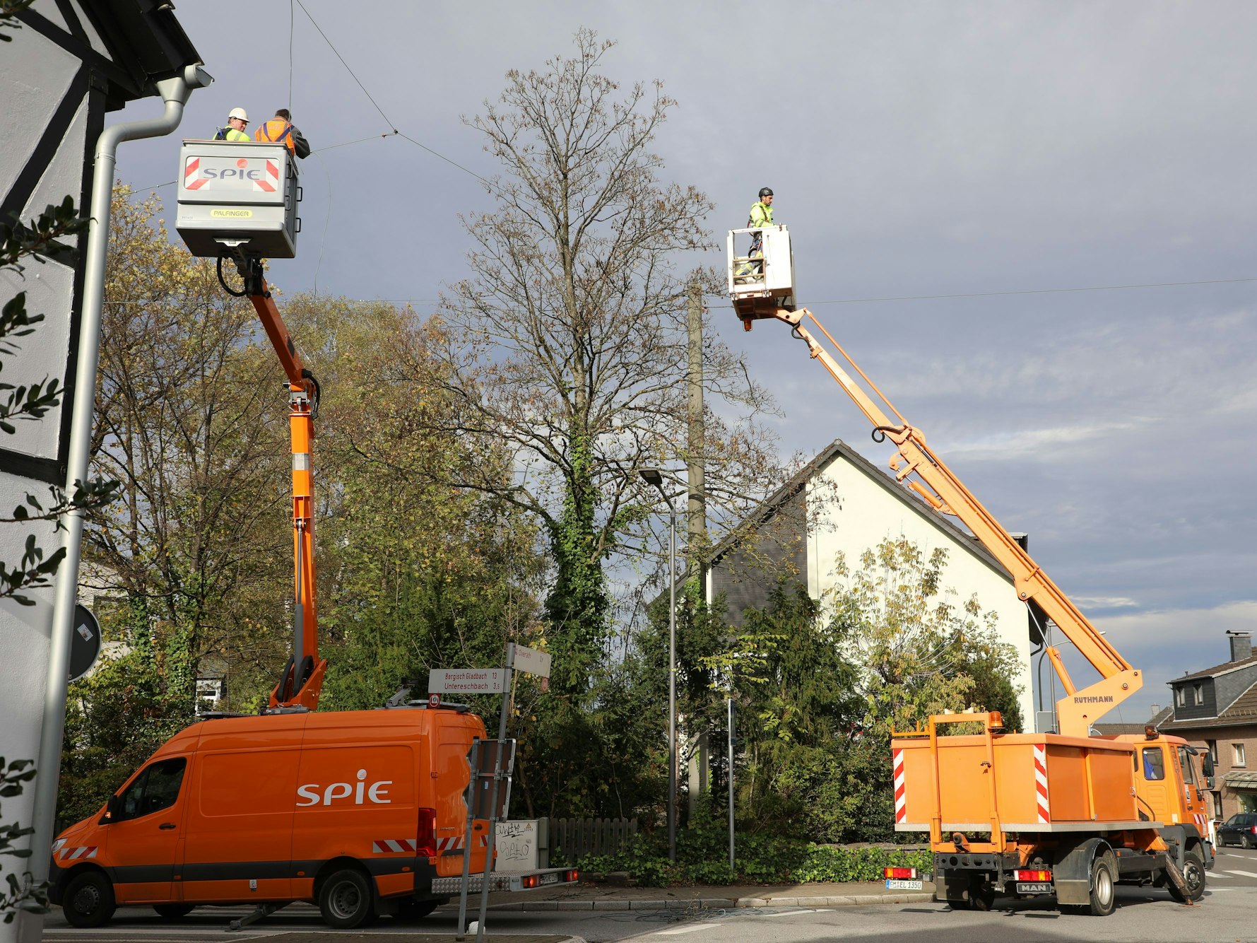Monteure auf Hubsteigern demontieren Drahtseile mit Straßenlaternen, die über der Straße in OIverath-Heiligenhaus angebracht sind.