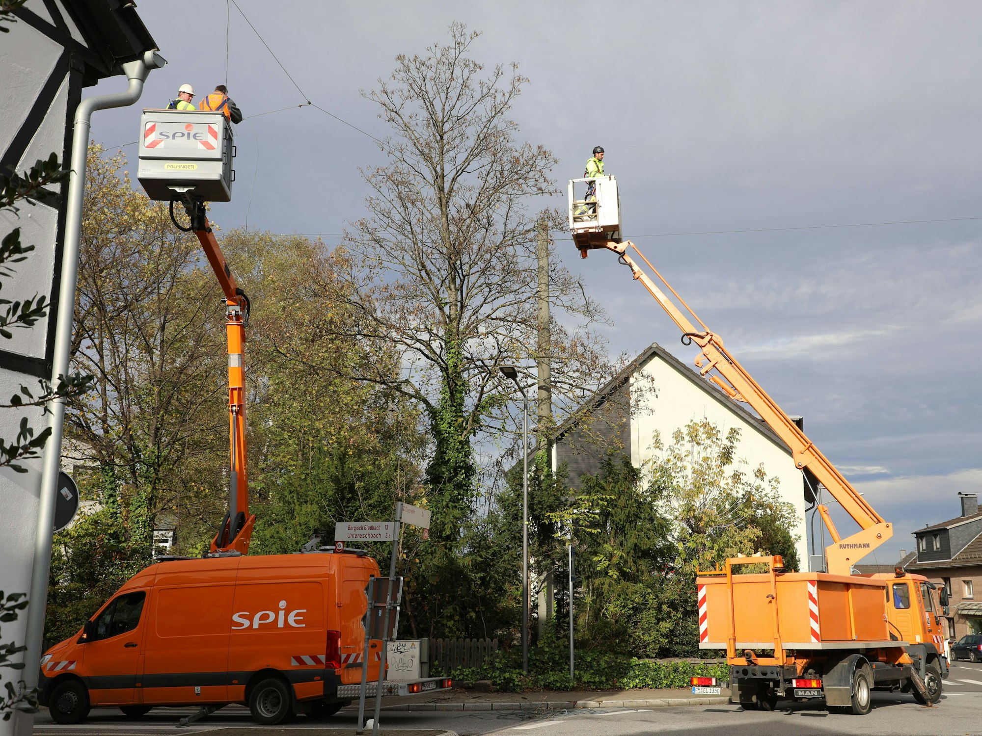 Monteure auf Hubsteigern demontieren Drahtseile mit Straßenlaternen, die über der Straße in OIverath-Heiligenhaus angebracht sind.