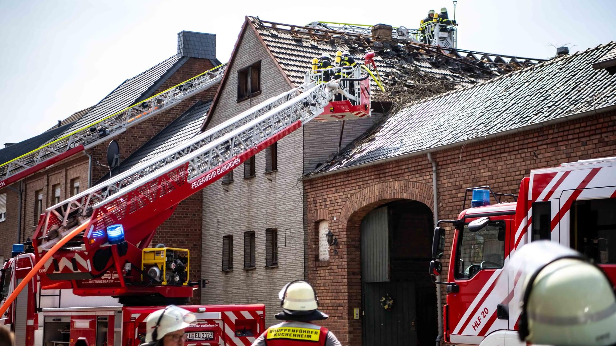 Auf dem Bild ist zu sehen, wie das Feuer den Dachstuhl beschädigt hat. Die Feuerwehr begutachtet mithilfe von zwei Drehleitern den Schaden.