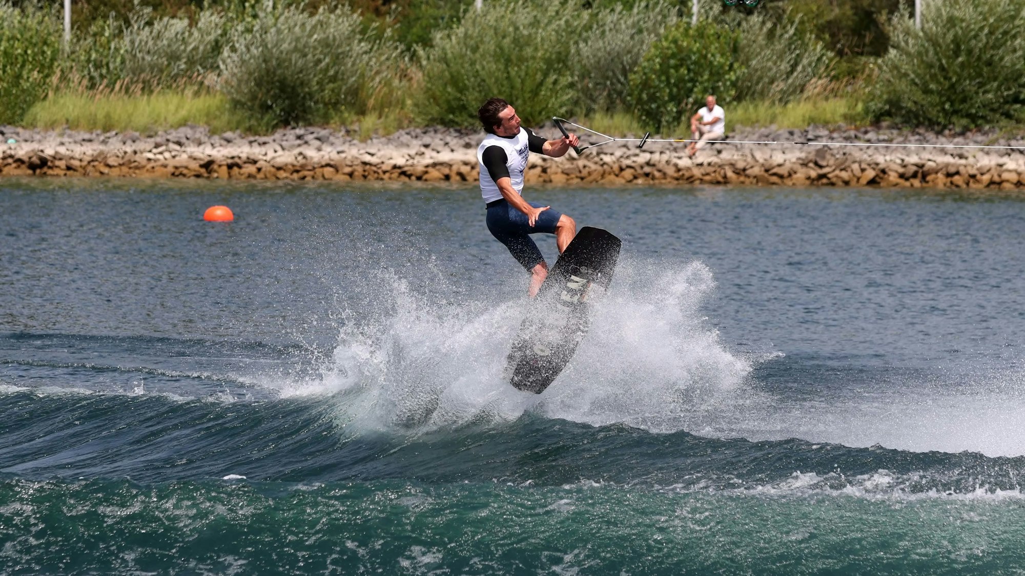 Ein Wakeboarder springt über eine Welle auf einem Fühlinger-See.