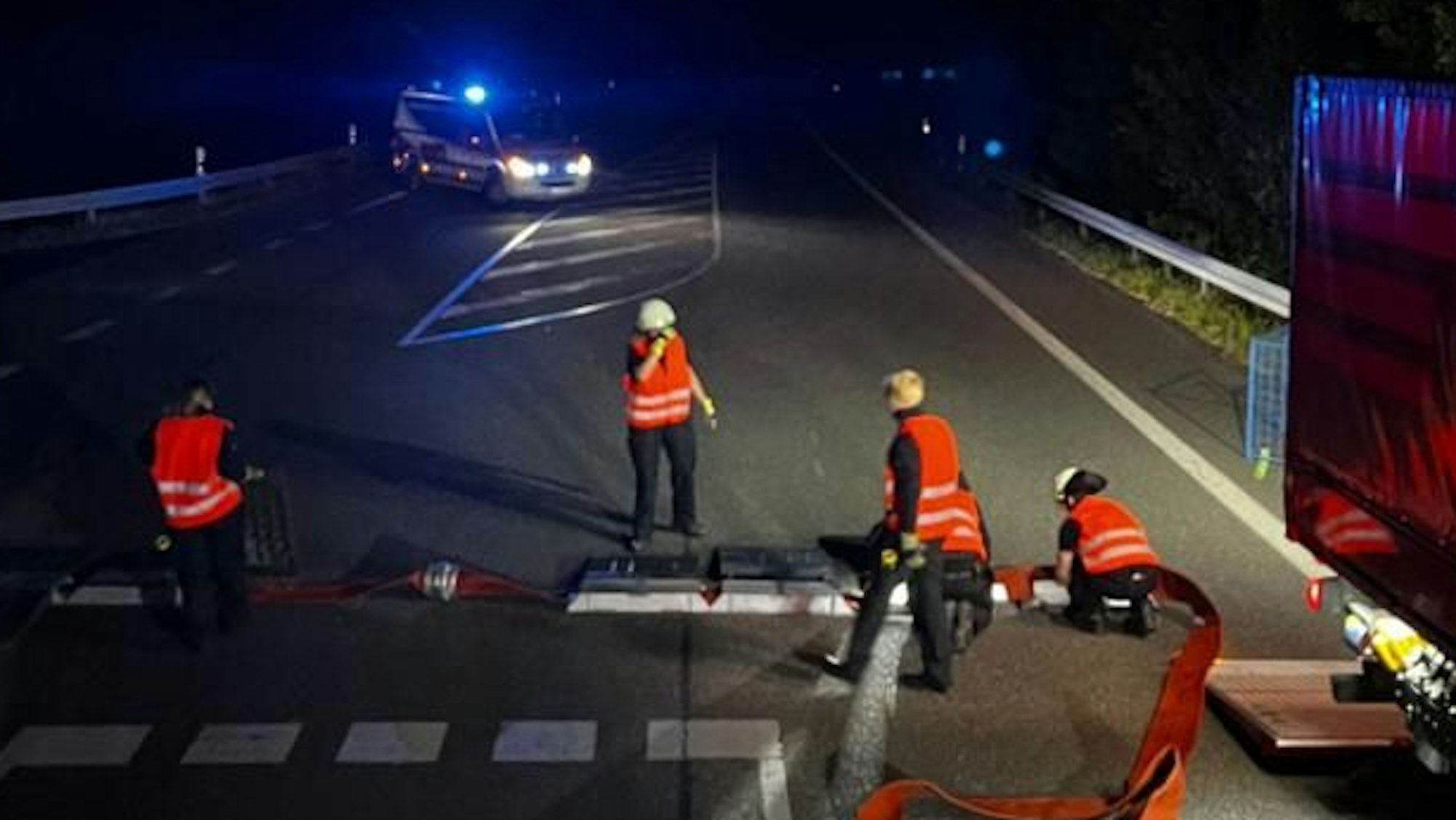 Einsatzkräfte stehen im Dunkeln im Schein von Blaulicht.
