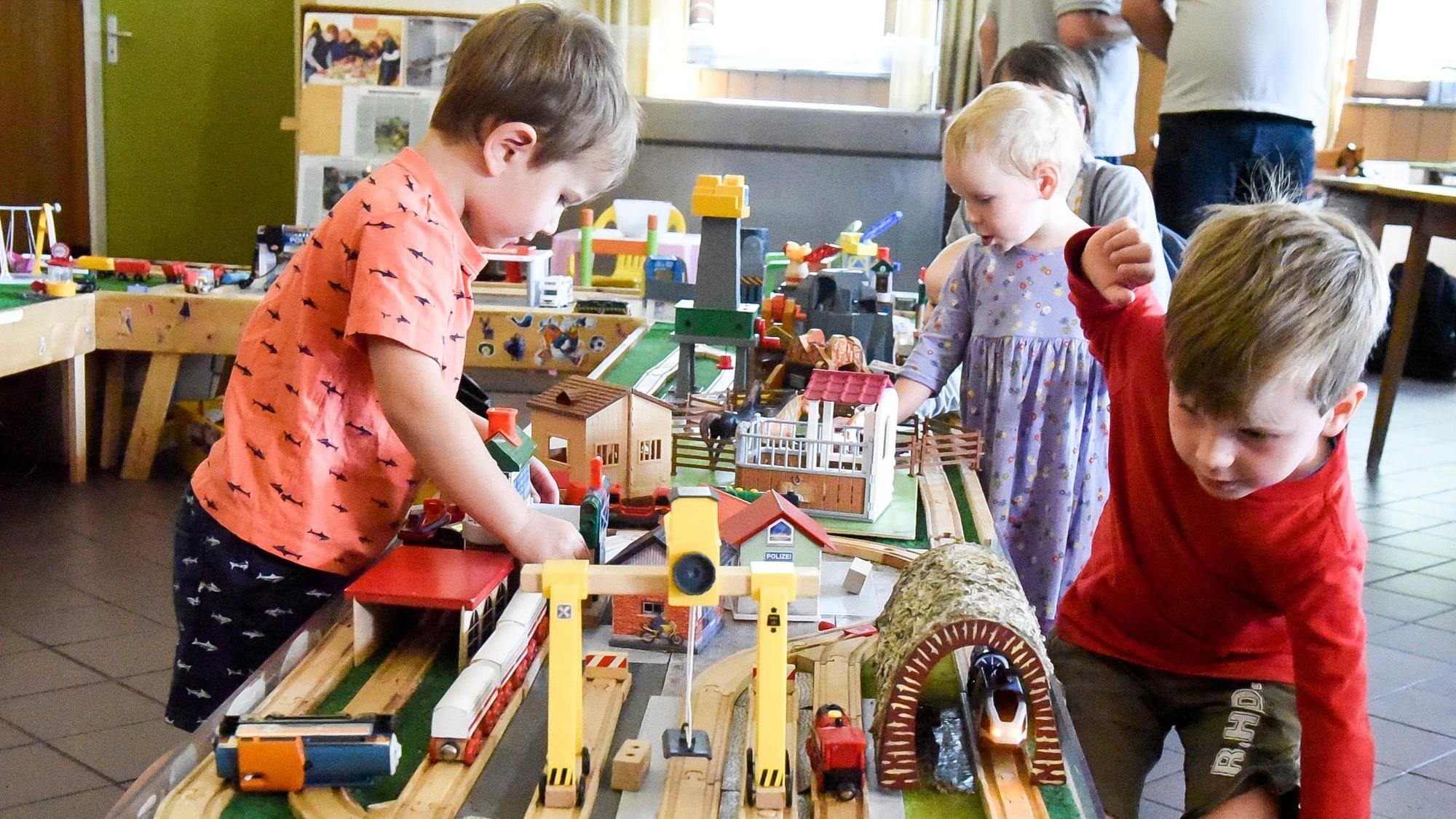 Das Foto zeigt, wie Kinder mit einer Holzeisenbahn spielen.