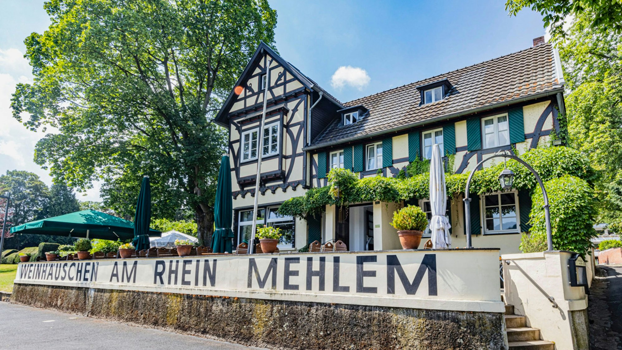 Die idyllische Terrasse des Weinhäuschens am Rhein von Außen betrachtet.
