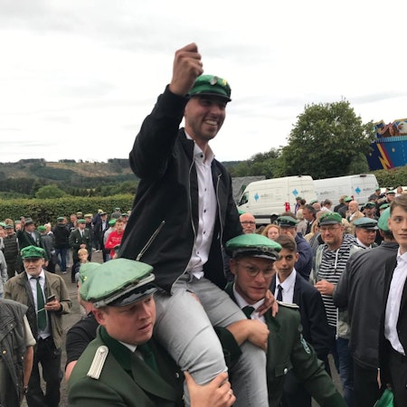 Mehrere Schützenbrüder heben einen ihrer Schützen auf Schultern in die Höhe.