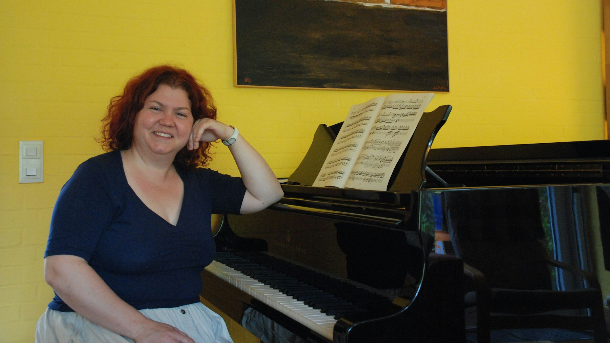 Ana Mirabela Dina sitzt an einem Flügel und schaut in die Kamera.
