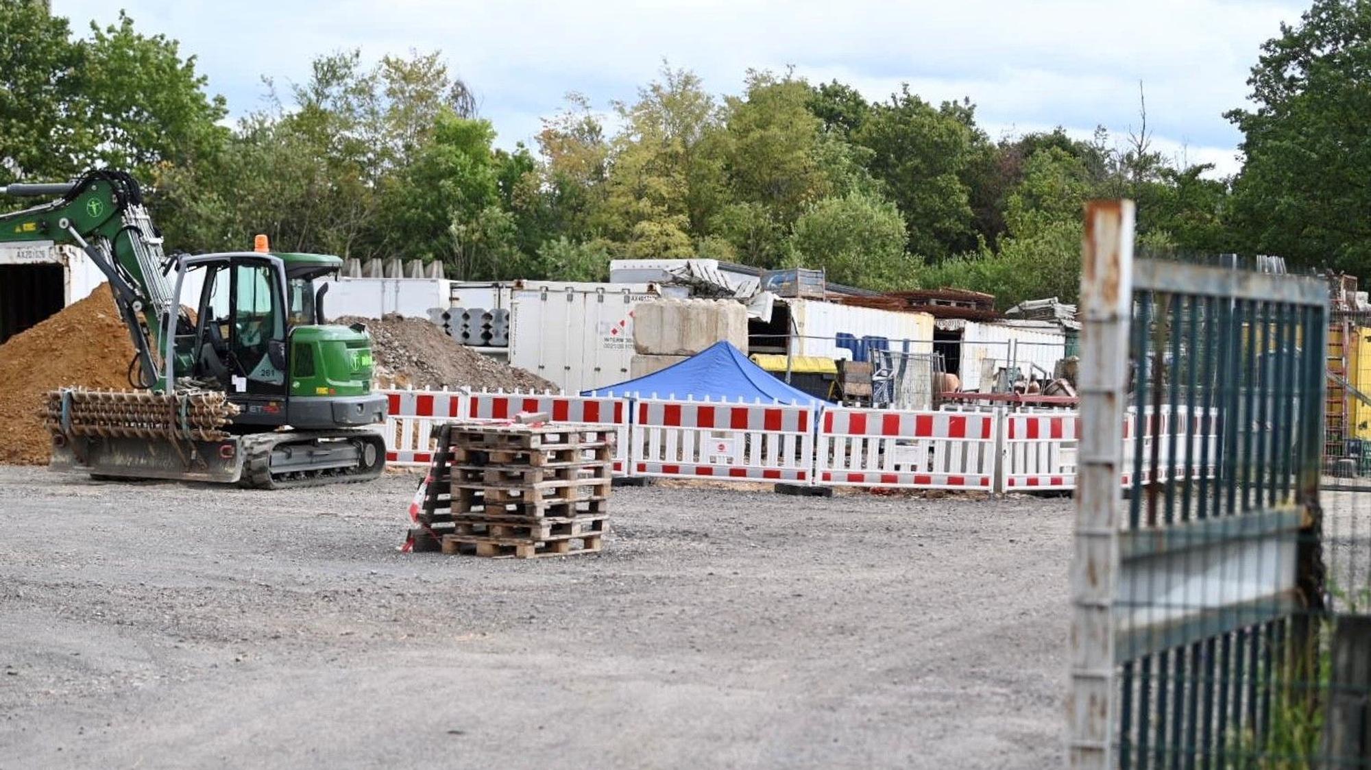 Auf einer Baustelle steht ein Bagger, daneben ist ein Bereich mit Gittern abgesperrt.