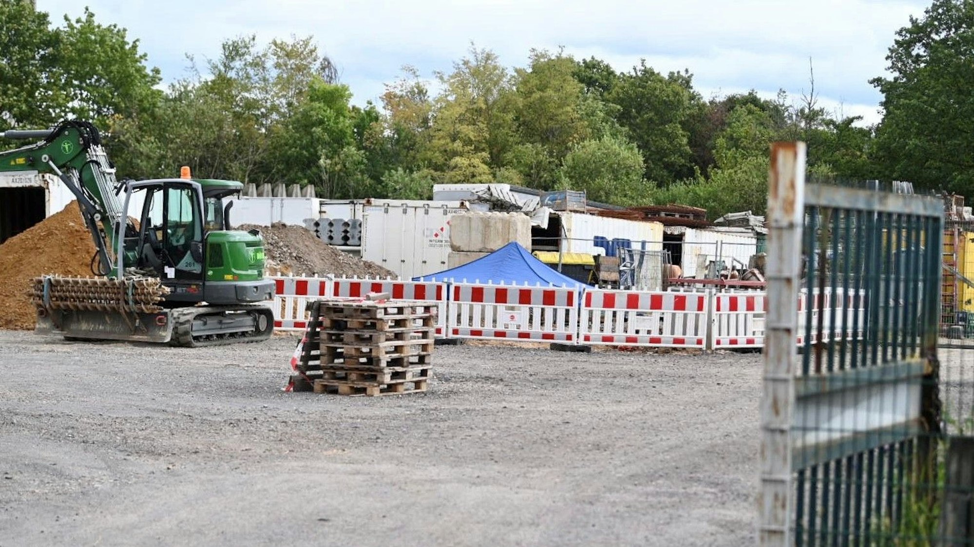 Auf einer Baustelle steht ein Bagger, daneben ist ein Bereich mit Gittern abgesperrt.