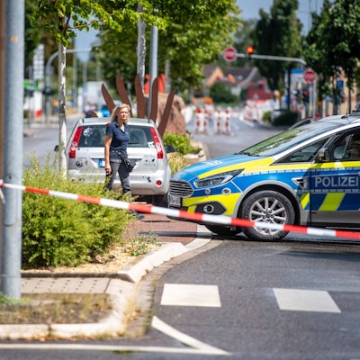 Eine Straße ist mit Flatterband und einem Polizeifahrzeug abgesperrt.