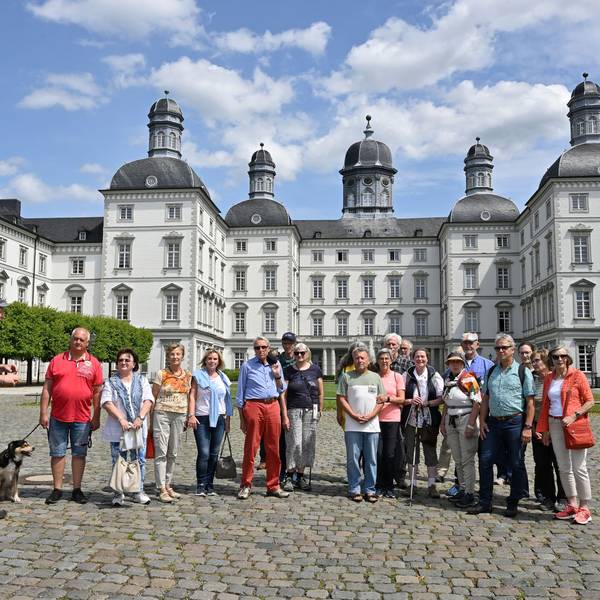 Eine Wandergruppe steht mit Naturparkführer und Redaktionsleiter Guido Wagner im Hof von Schloss Bensberg.