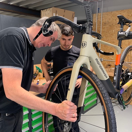 Das Firmengebäude der Firma Veloland ist fast fertig. Zweiradmechaniker bei der Endmontage eines Fahrrades.