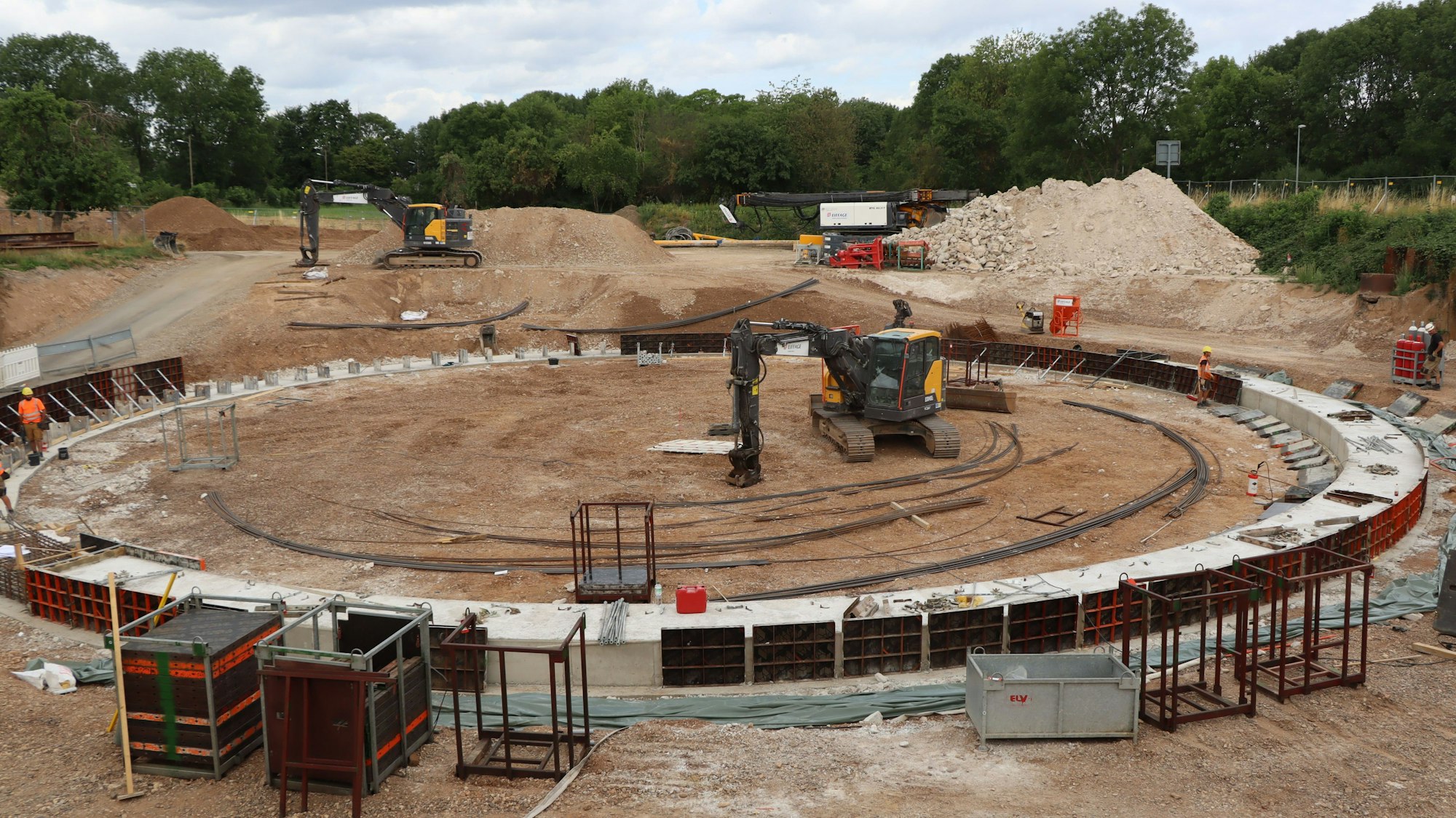 Das Bild zeigt die Baustelle des Wasserauffangbeckens. In der Mitte steht ein Bagger.