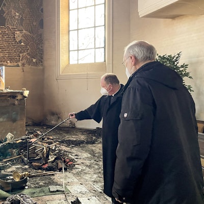 Weihbischof Ansgar Puff (r.) und Dechant Martin Kürten stehen in der zerstörten Pfarrkirche Kreuzerhöhung und betrachten das Ausmaß der Schäden. Für den Brand im Februar vergangenen Jahres muss sich jetzt ein Reichshofer vor dem Landgericht in Koblenz verantworten.