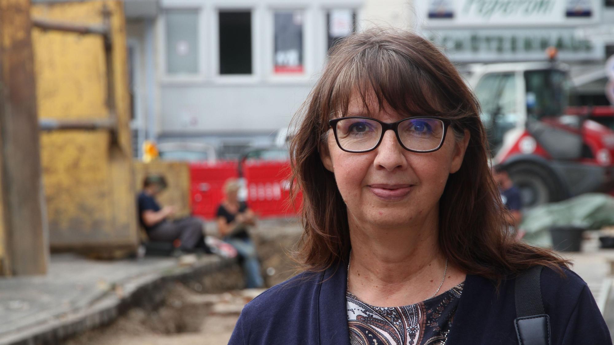 Eine Frau steht vor einer Ausgrabungsstätte.
