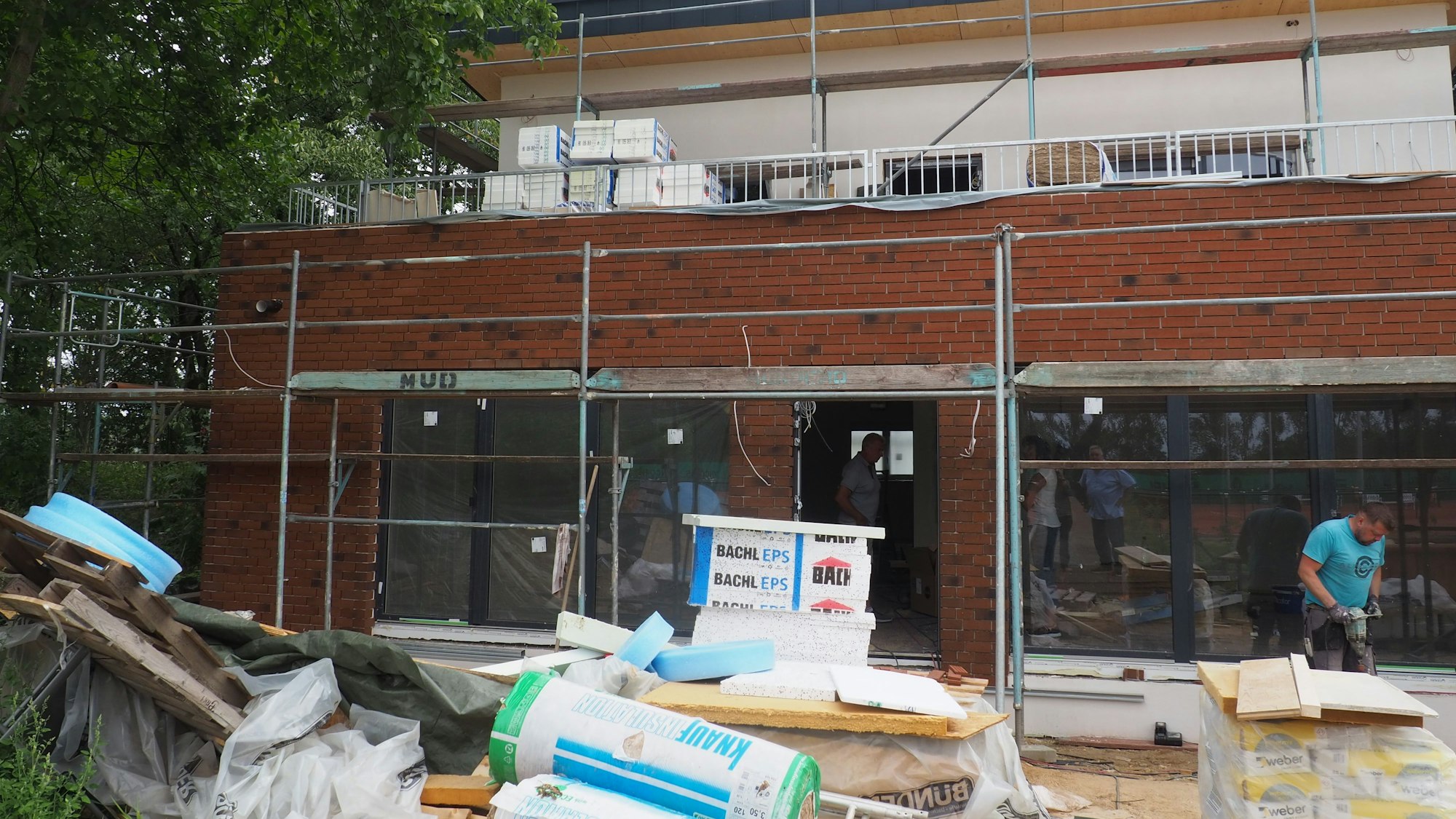 Vor einem eingerüsteten Haus liegen Baumaterialien.