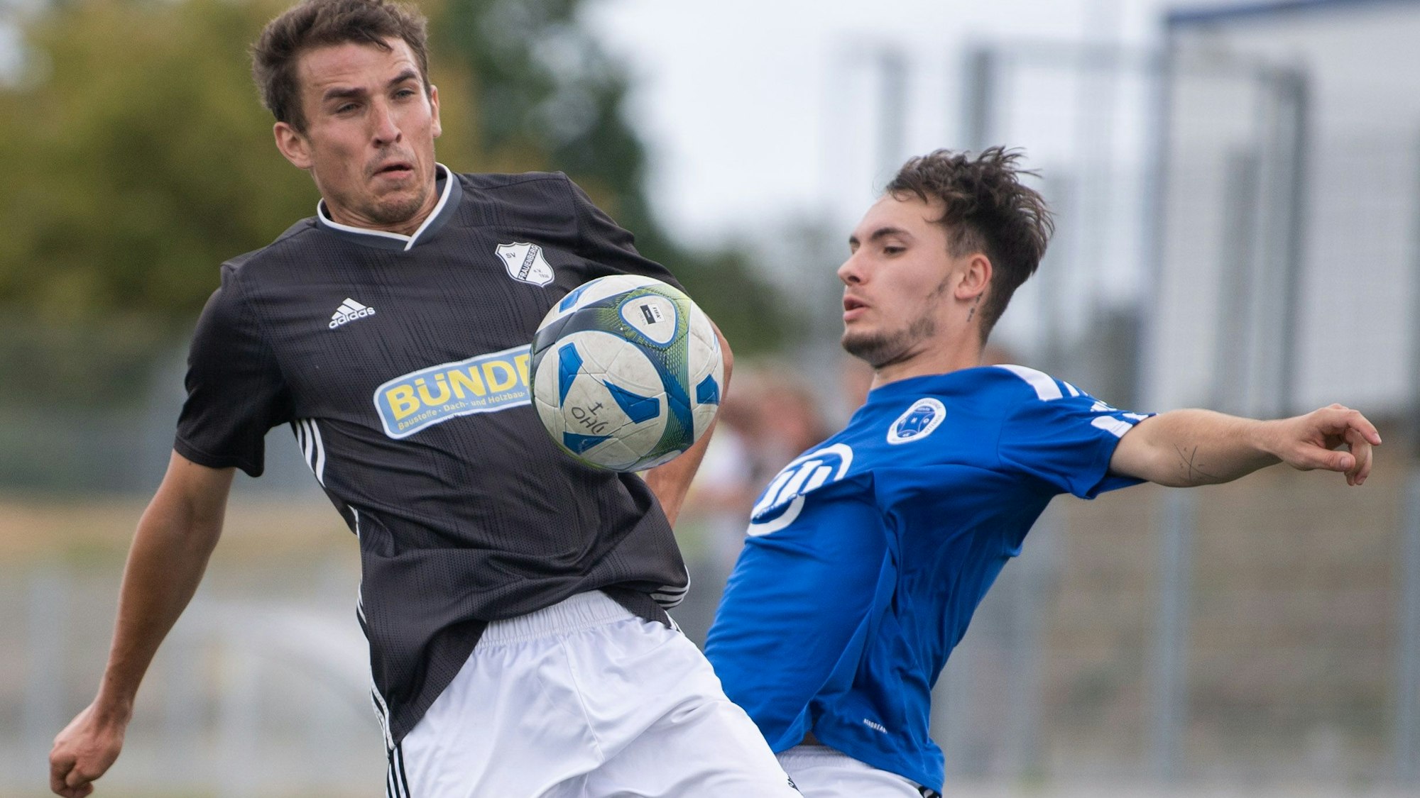 Zwei Fußballer duellieren sich in der Luft beim Kampf um den Ball.