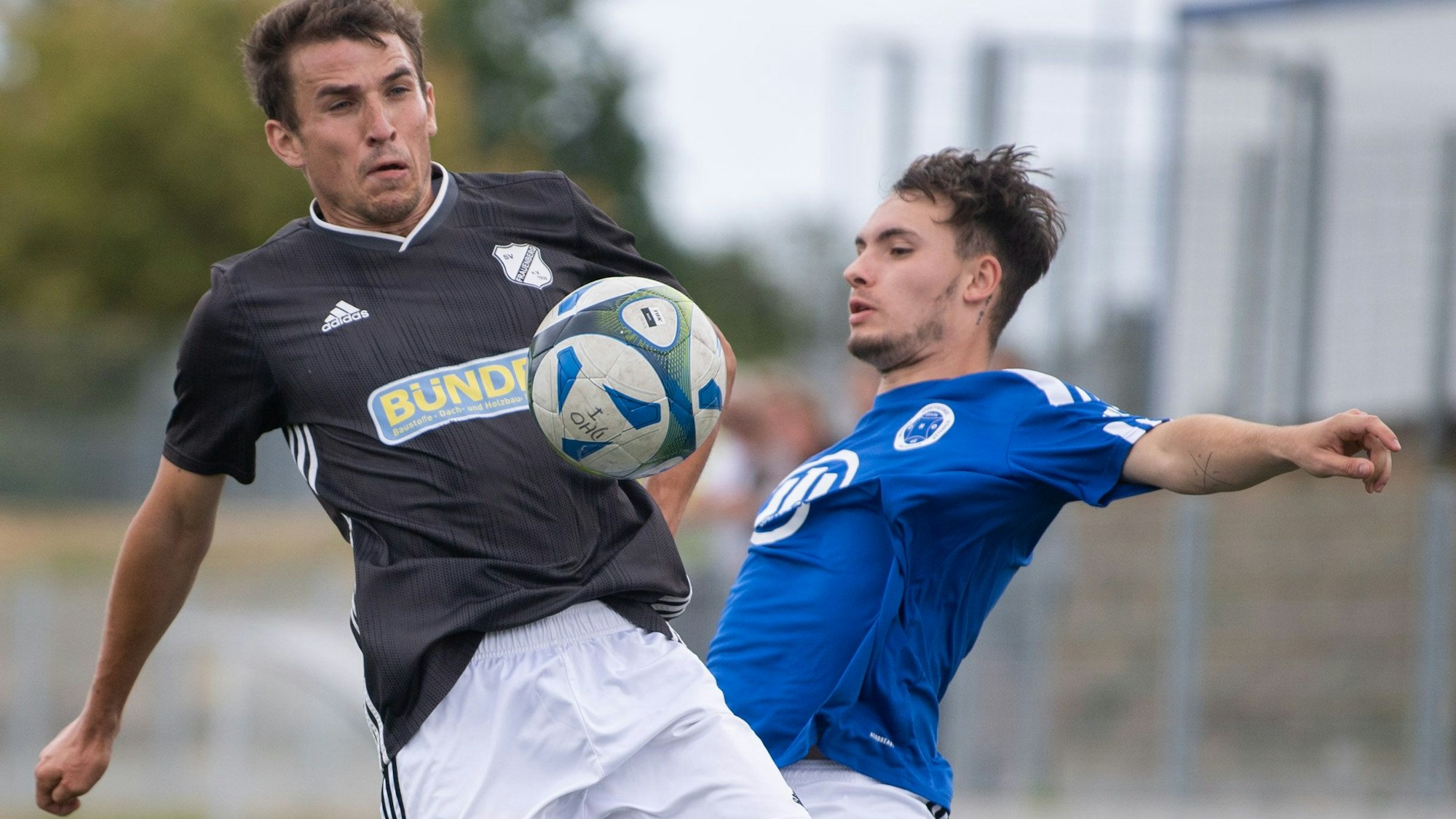 Zwei Fußballspieler versuchen, an den Ball zu kommen, der sich auf Brusthöhe zwischen ihnen befindet.