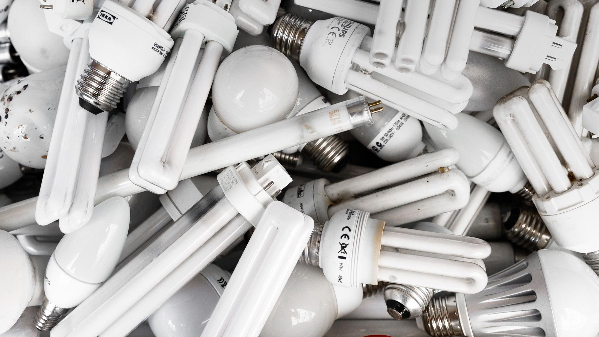 Verschiedene Lampen, darunter Leuchtstoffröhren, liegen kreuz und quer auf einem Haufen.