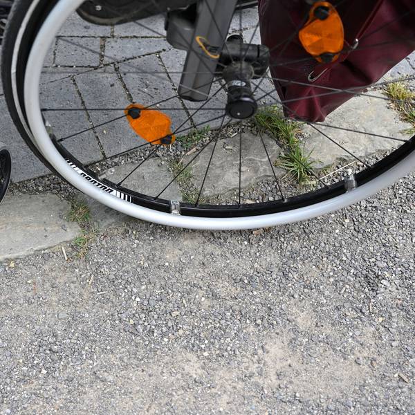 Ein Rollstuhl steht auf einem gepflasterten Weg.