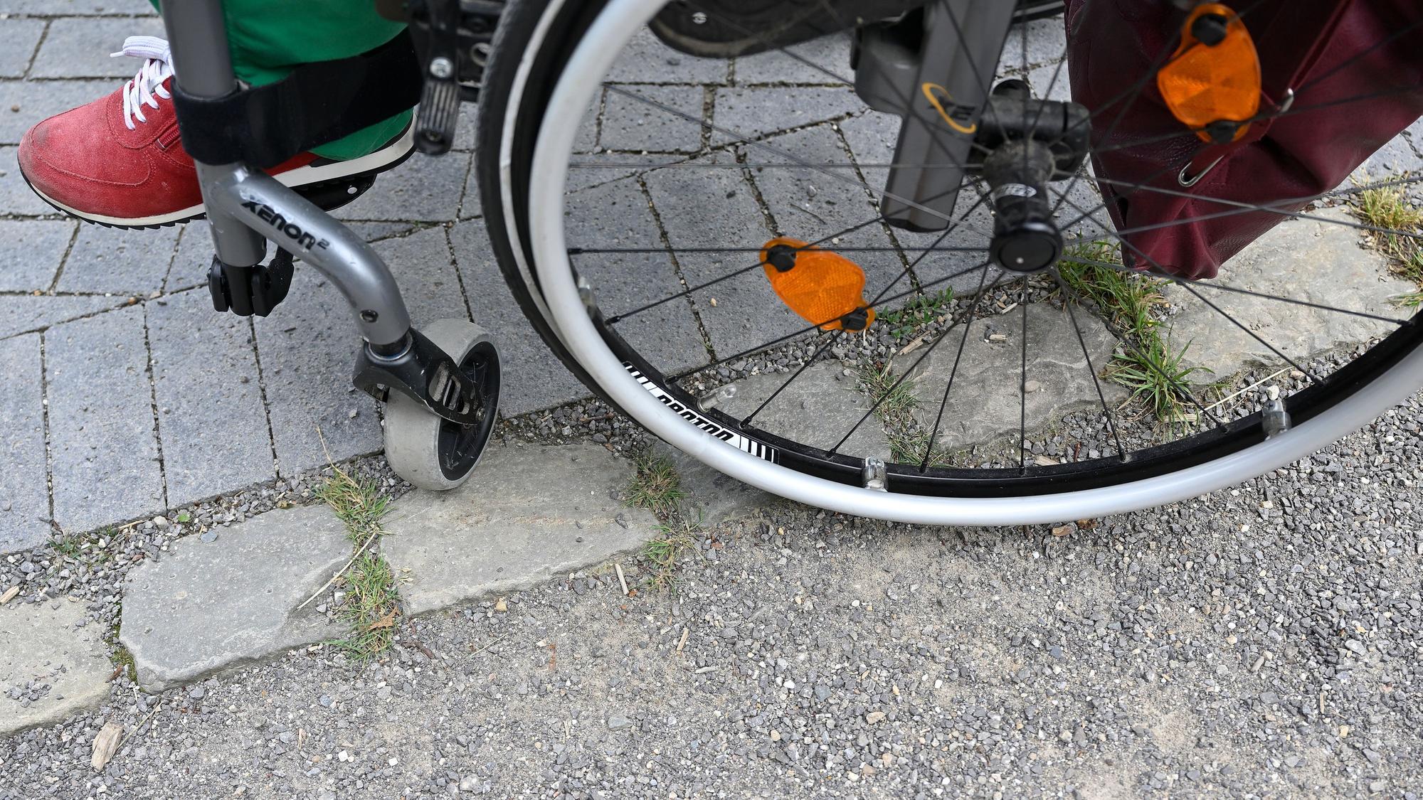 Ein Rollstuhl steht auf einem gepflasterten Weg.