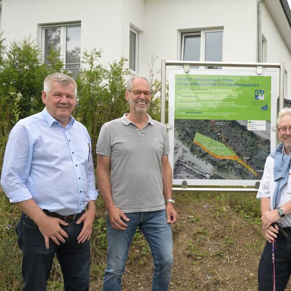 Fünf Männer stehen vor einer Schautafel, die den Bürgerwald in Steinenbrück erläutert.
