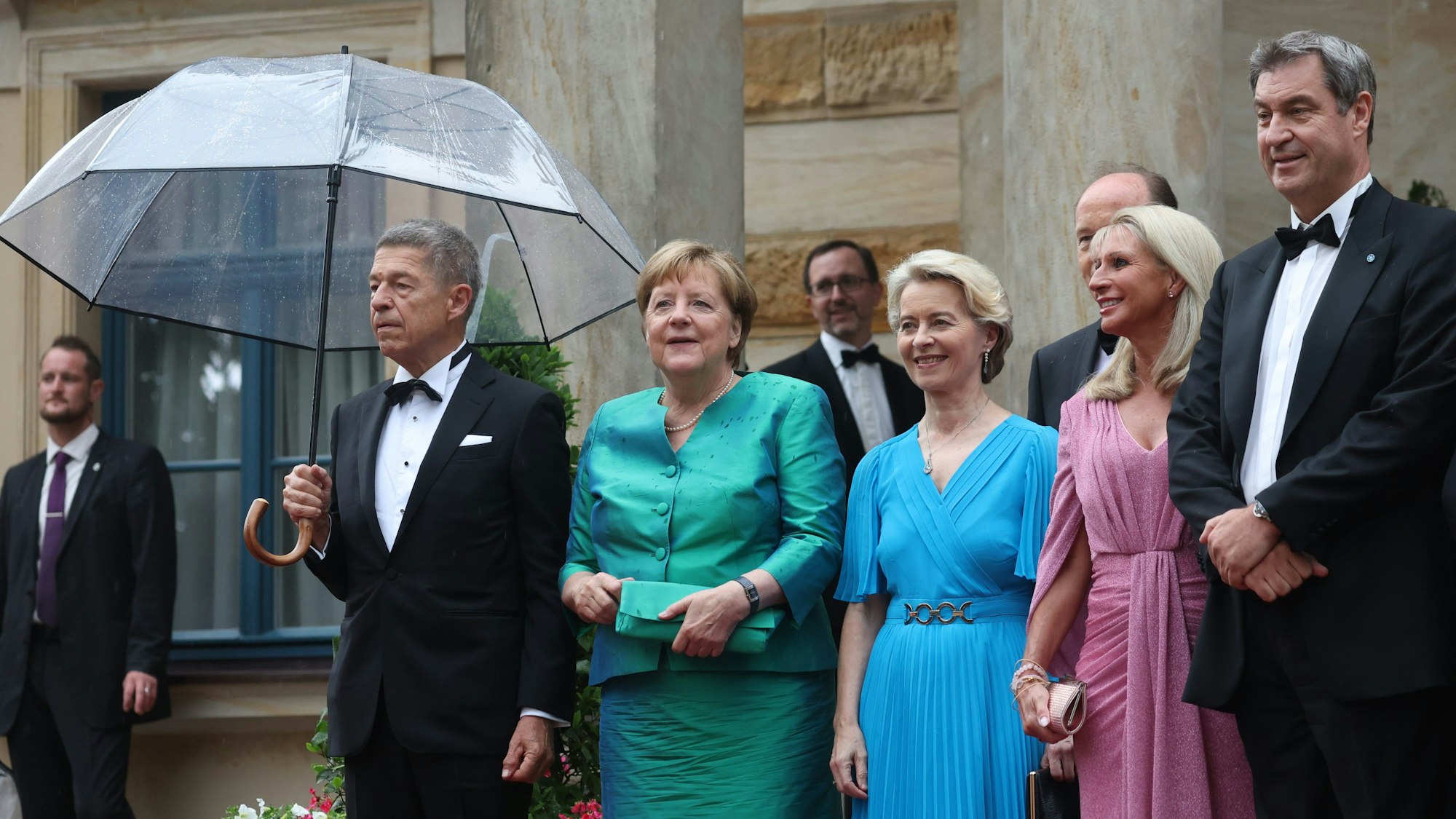 Bayern, Bayreuth: Ex-Bundeskanzlerin Angela Merkel (CDU) und Ehemann Joachim Sauer, Ursula von der Leyen (CDU), Präsidentin der EU-Kommission, und Ehemann Heiko von der Leyen, Markus Söder (CSU), Ministerpräsident Bayerns, und Ehefrau Karin stehen zu der Eröffnung der Richard-Wagner-Festspiele vor dem Festspielhaus auf dem Grünen Hügel.