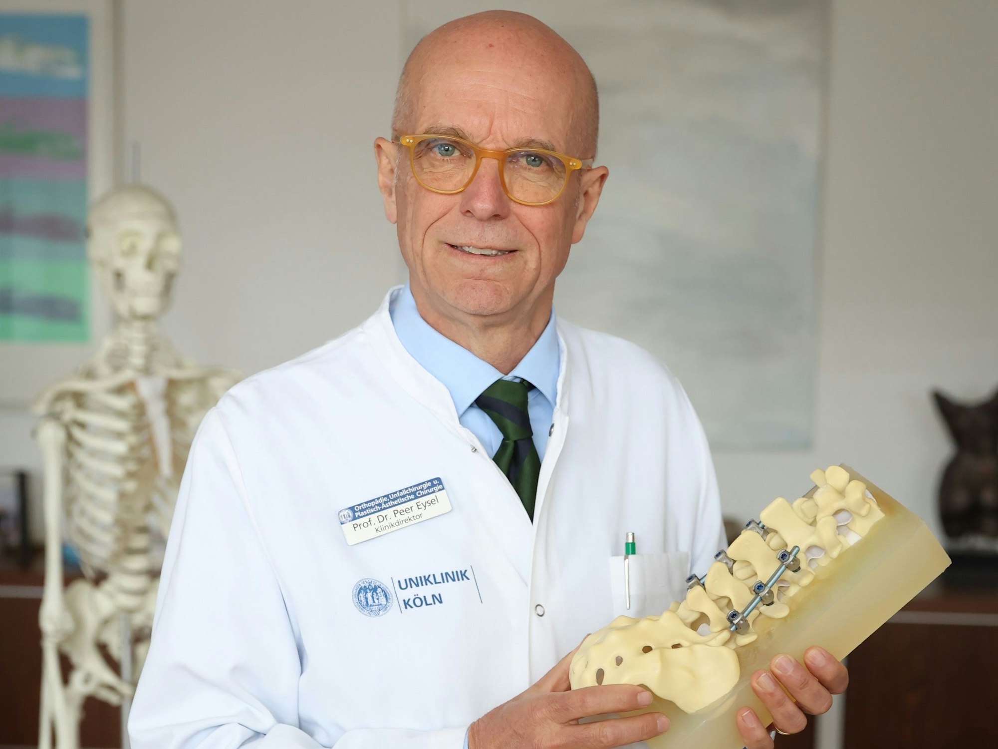 Professor Peer Eysel hält eine Wirbelsäulen-Nachbildung in seinen Händen.