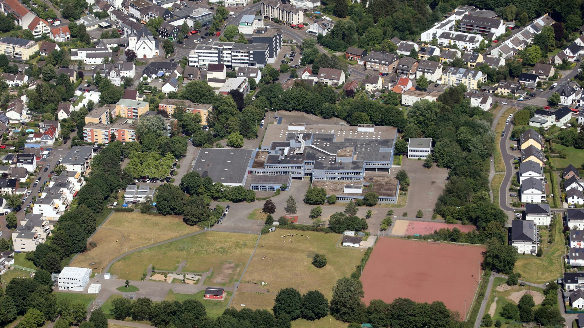 Das 1973 gebaute Schulgebäude der Integrierten Gesamtschule Paffrath. Davor das Sportgelände, ringsherum Wohnhäuser.