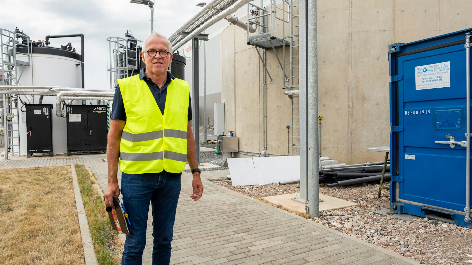 Der Ingenieur mit einer gelben Signalweste steht auf dem Betriebsgelände des Unternehmens.