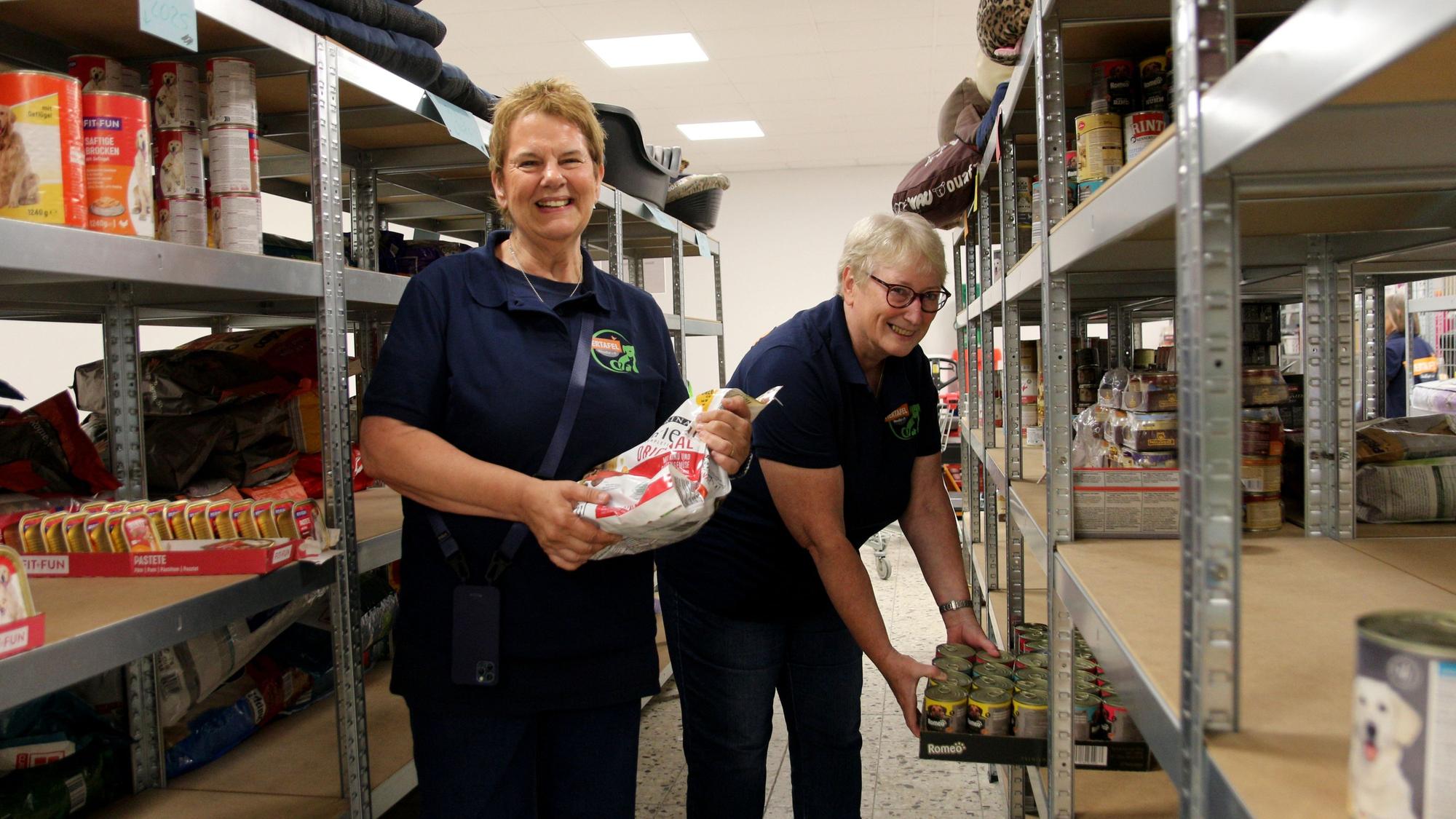 Zwei Frauen räumen in einem Lagerraum Tierfutter in Regale.