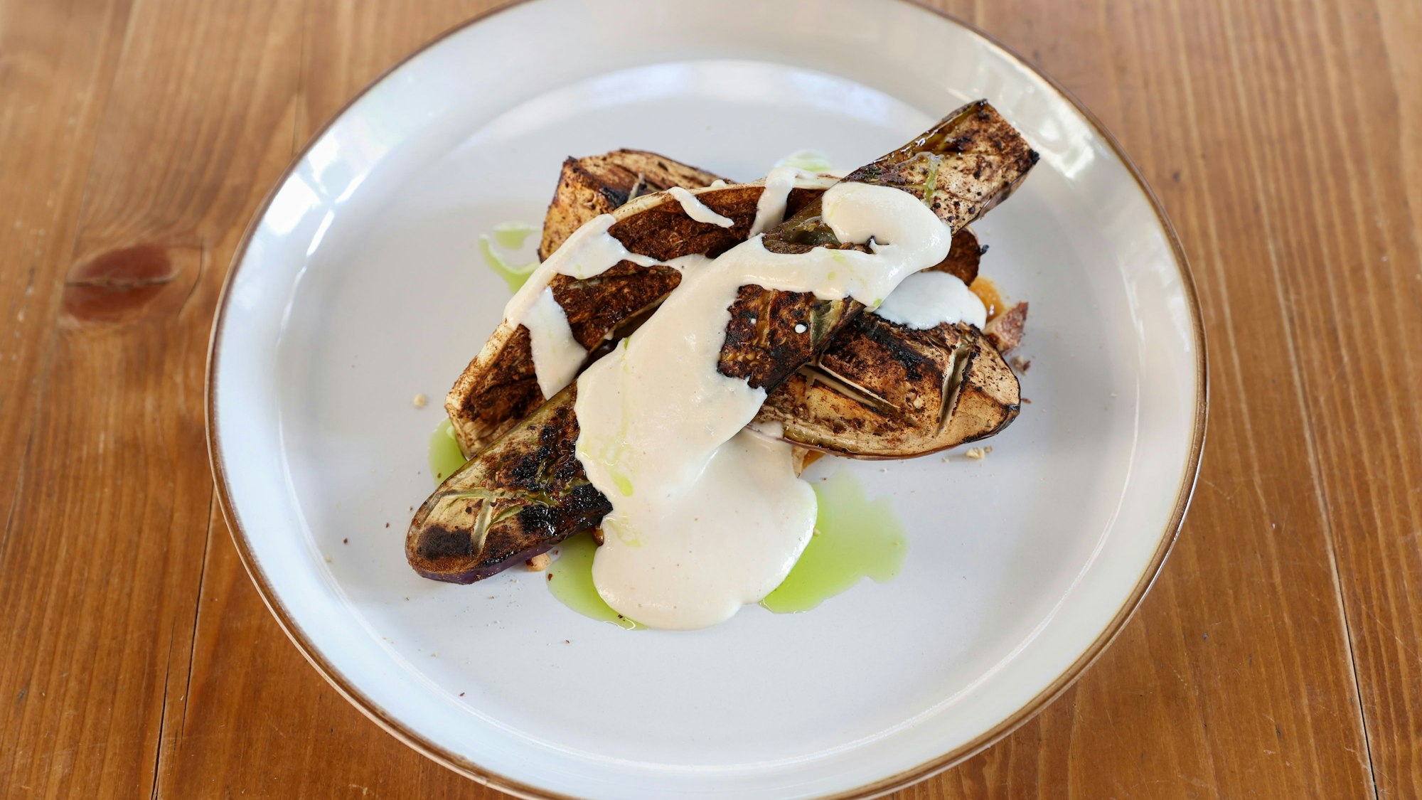 geschmorte Aubergine mit Schmand auf einem Teller angerichtet