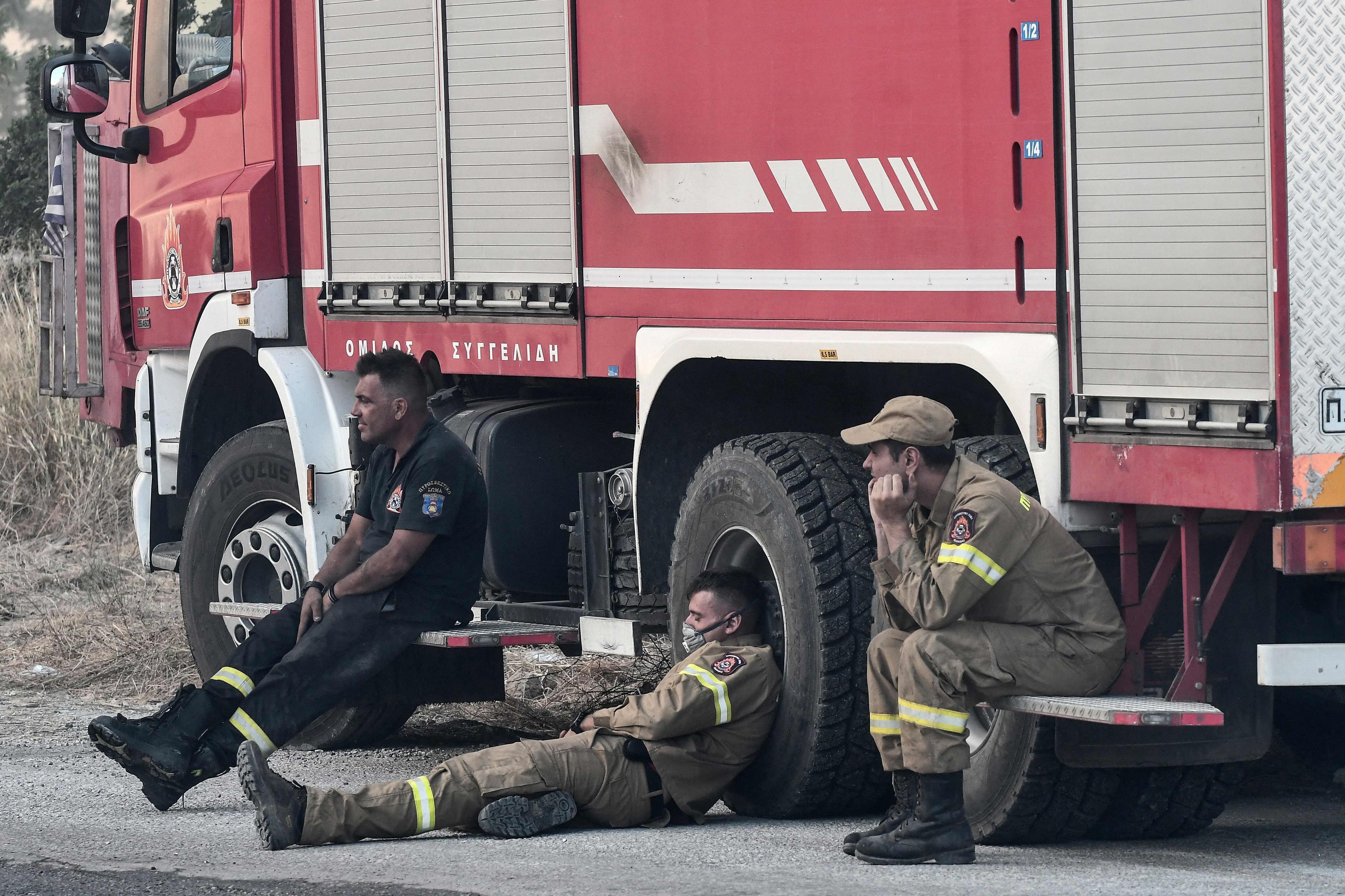 Feuerwehrleute ruhen sich während der Rettungsarbeiten kurz aus.