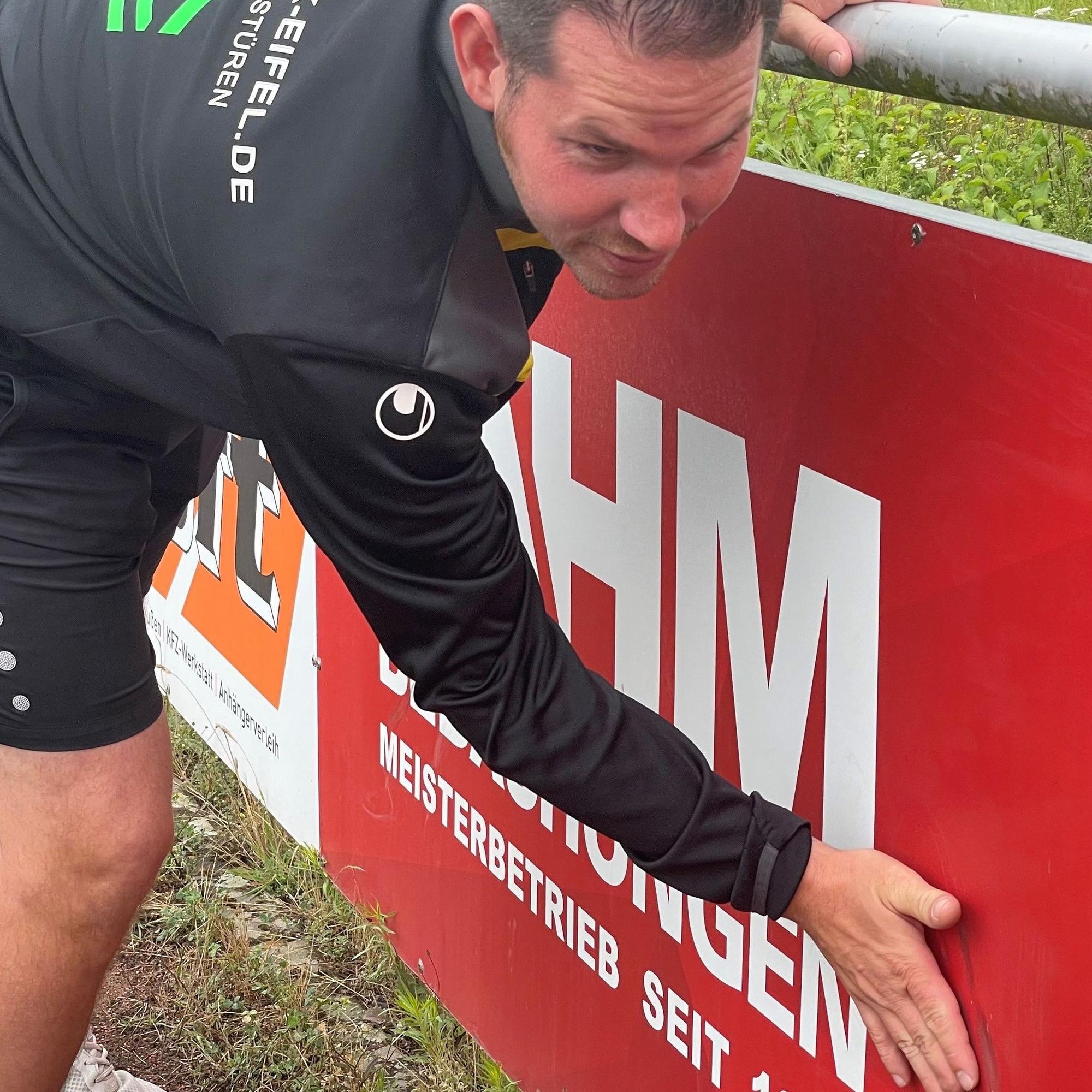 Ralf Heser zeigt die beschädigte Werbebande.